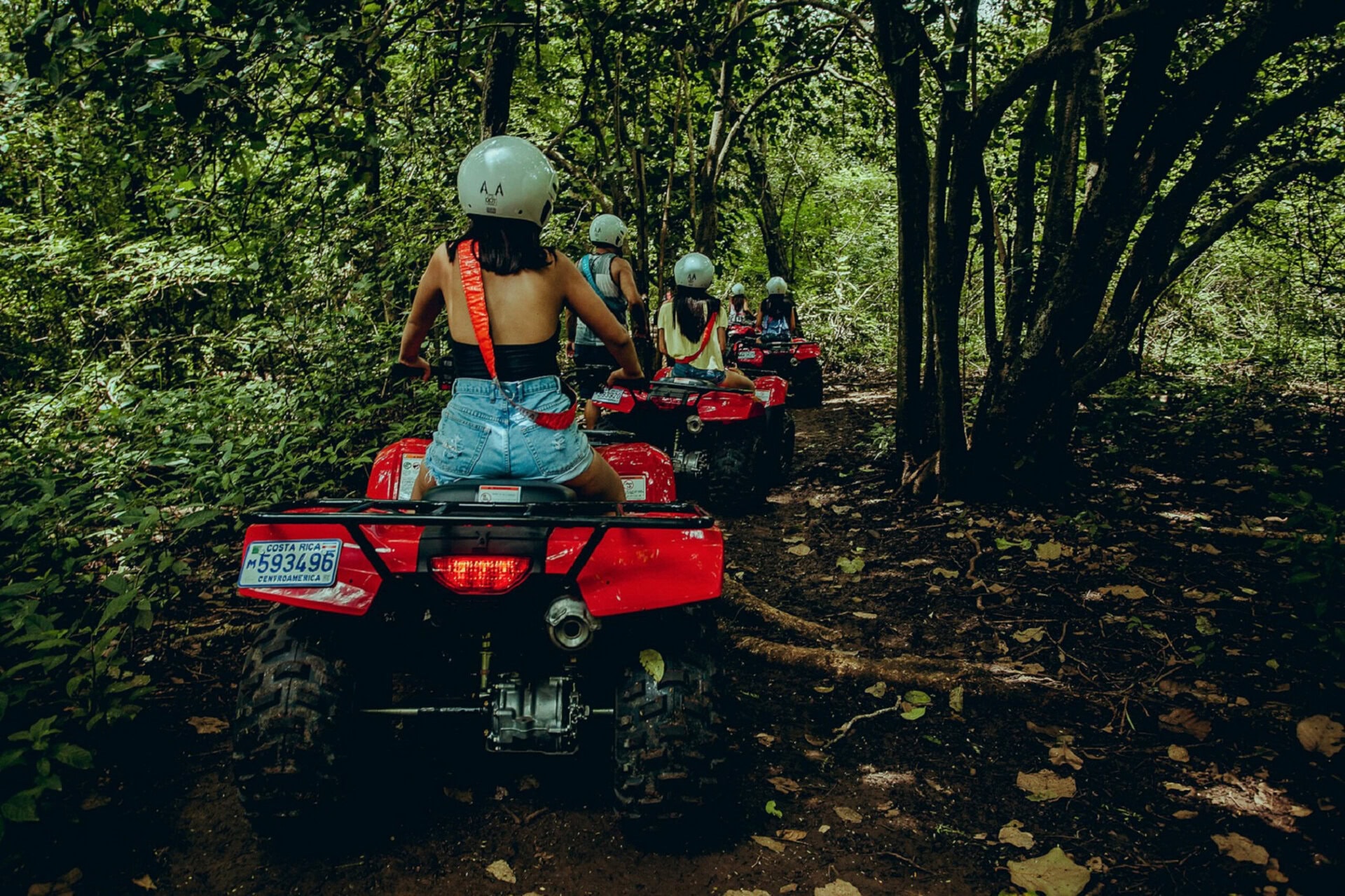 All pictures taken in Opulencia, Nosara, Costa Rica, featuring children riding all-terrain vehicles through lush forest trails.